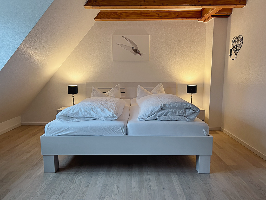 Ferienhaus Classic – Schlafzimmer mit Doppelbett und sichtbaren Holzbalken