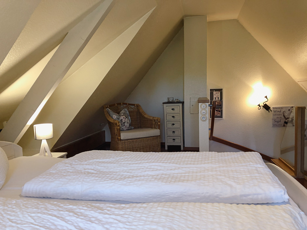 Ferienhaus Classic – Schlafzimmer unter der Dachschräge mit Korbsessel