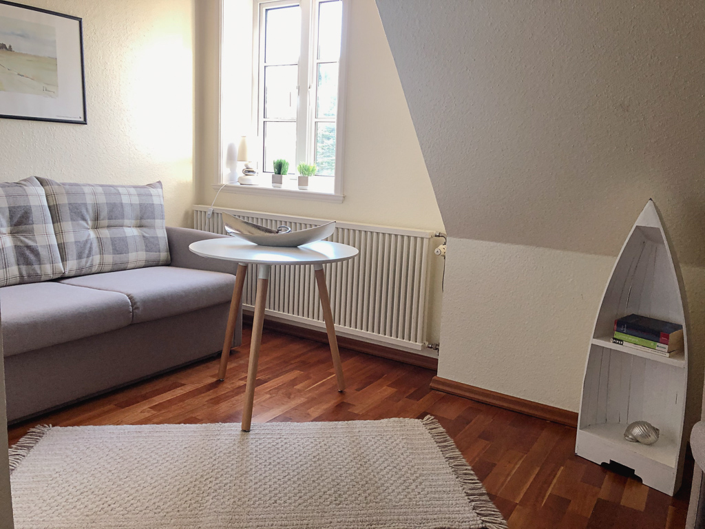 Ferienhaus Classic – Sitzecke mit Sofa und kleinem Tisch am Fenster